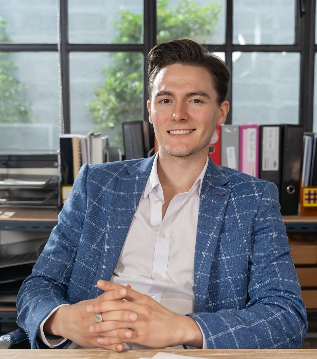 close-up-portrait-young-businessman-smiling-to-camera-in-office-e1658719612851.jpg